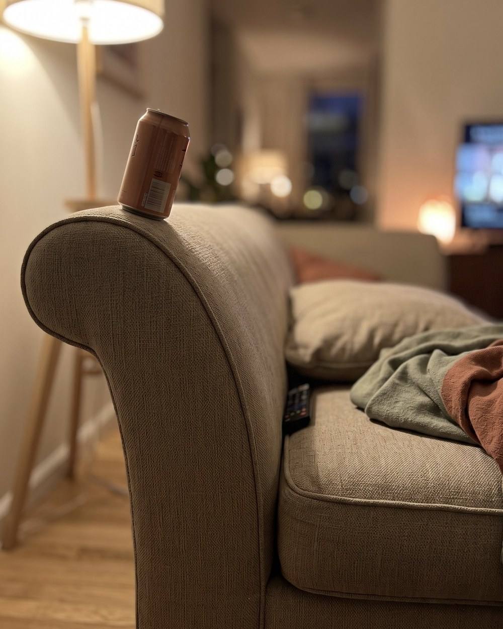 A tumbler balanced on the curve of a sofa arm.